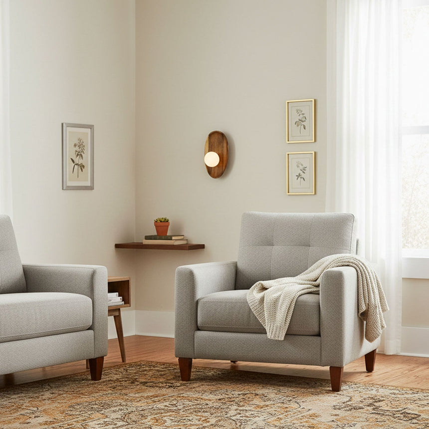 Sconce lit in a living room beside framed prints and a pale armchair