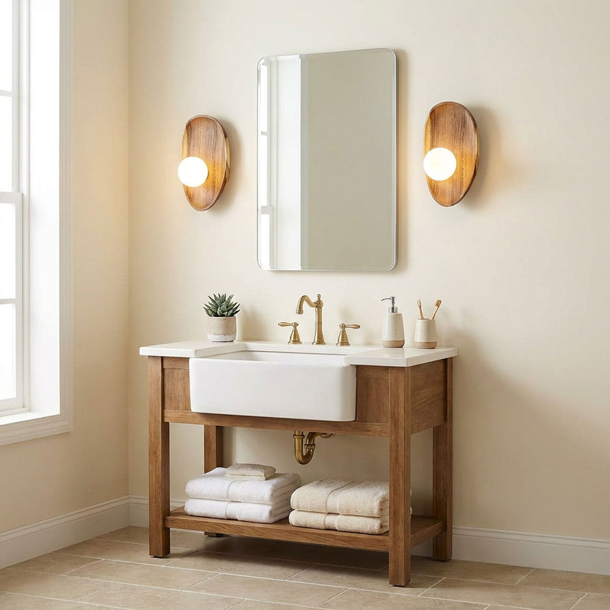 Two sconces lit either side of a bathroom mirror above a wood vanity