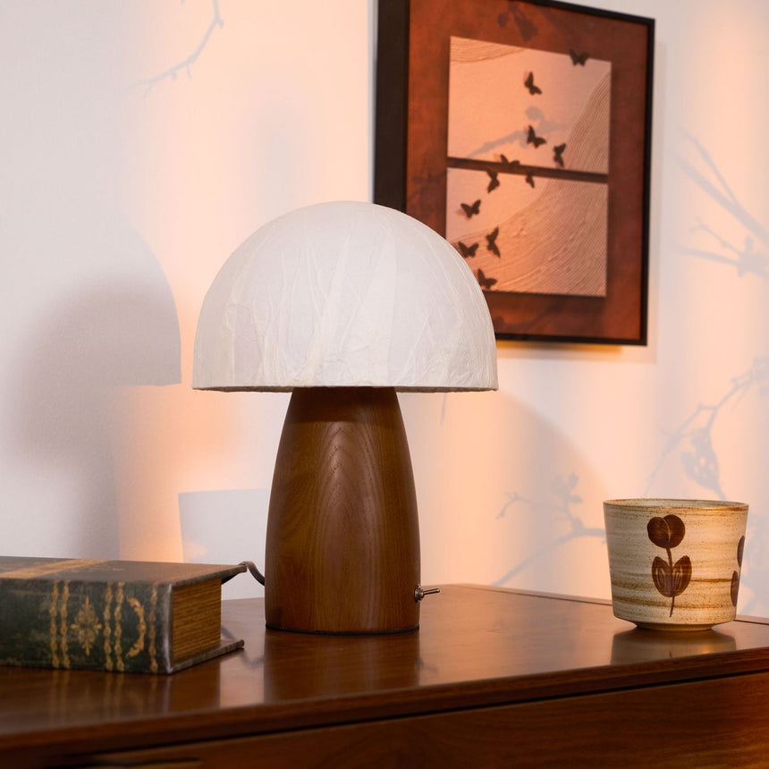 Mini table lamp on a wooden chest below a framed print of a tree
