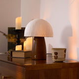 Mini table lamp lit on a sideboard beside lit candles and old books