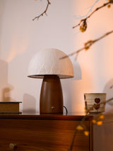 Mini table lamp on a wooden chest with a branch and a cup beside it