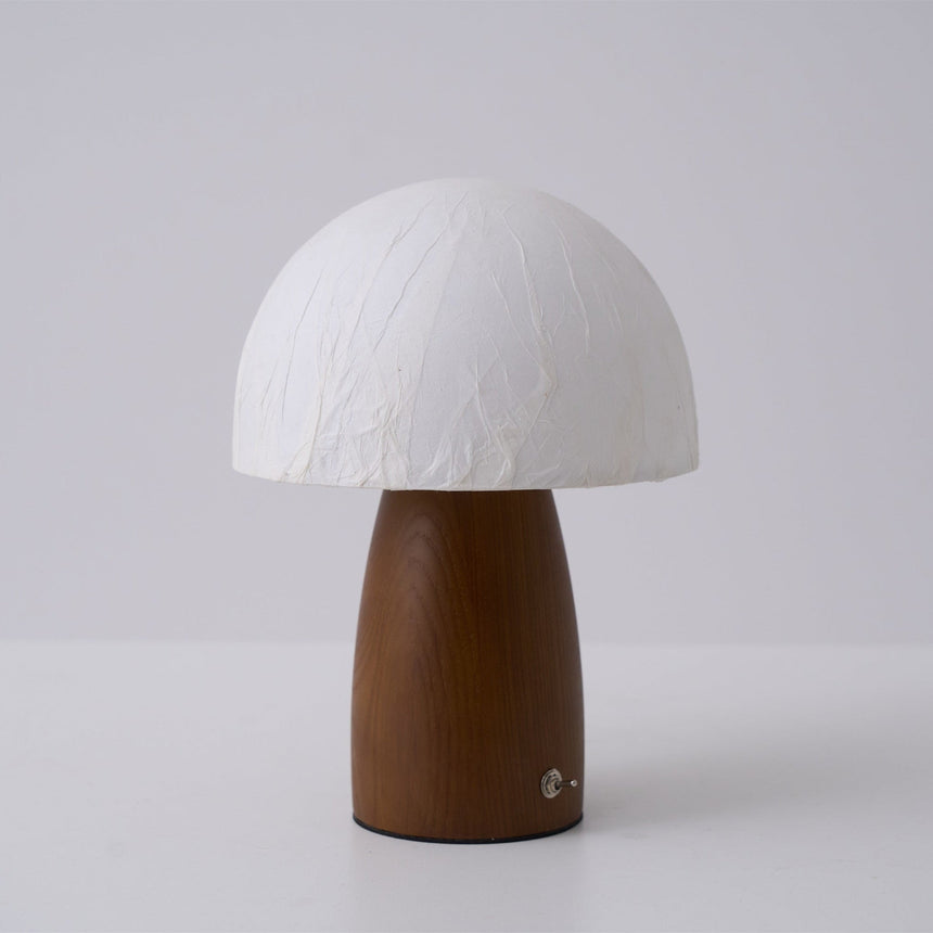 Mini table lamp lit on a bedside chest in a warm room at night