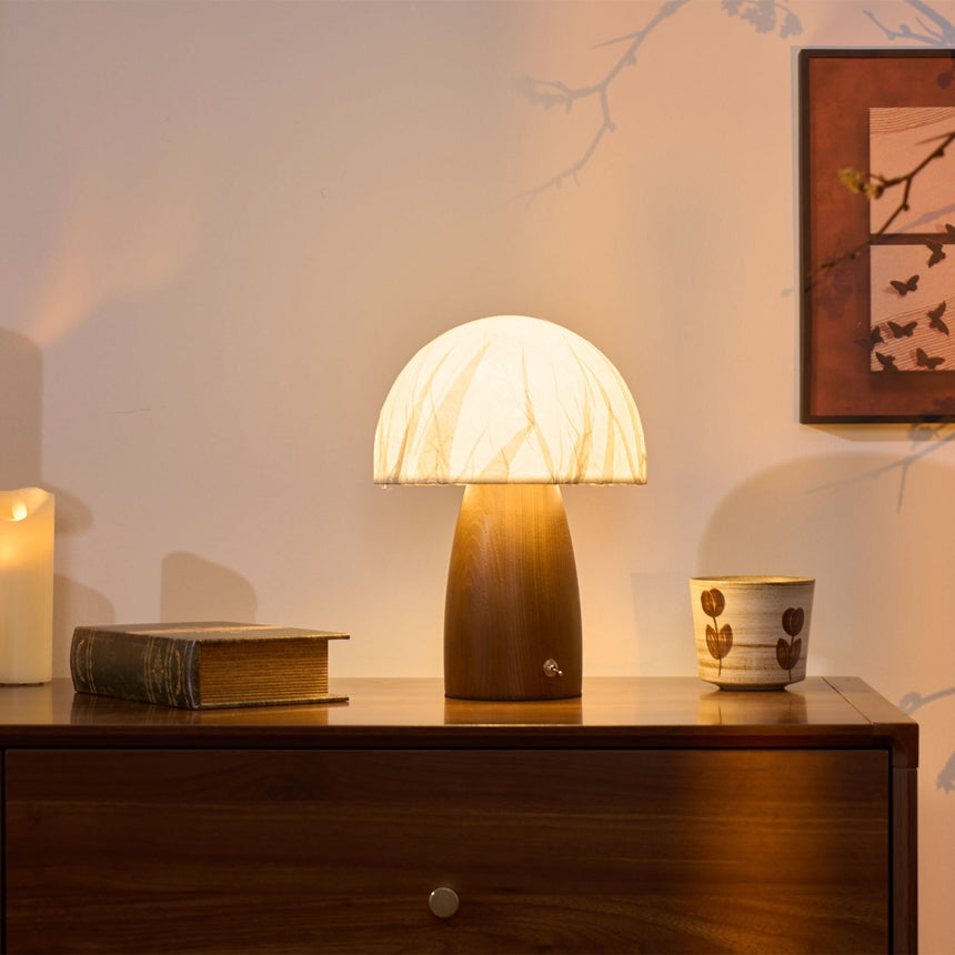 Mini table lamp lit on a wooden surface beside a patterned cup