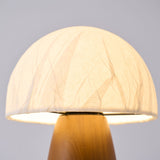 Close view of the crinkled paper dome lit from inside above the wood base