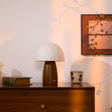 Mini table lamp unlit on a wooden chest beside a book and a cup