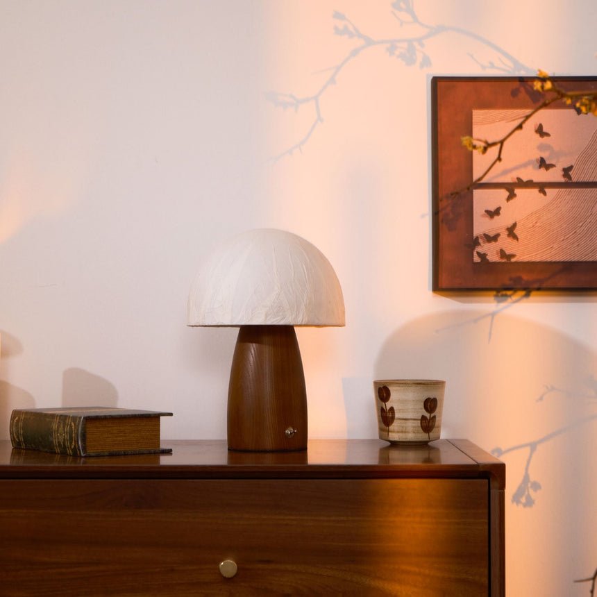 Mini table lamp unlit on a wooden chest beside a book and a cup