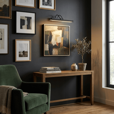Black bar lit above a framed picture on a wall of frames over a console table