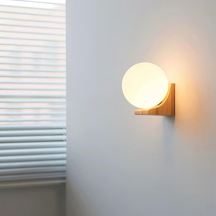 Sconce lit on a pale wall beside a window with the blind drawn down