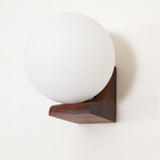 Close view of the glass sphere where it meets the folded wood bracket