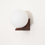 The pale wood bracket with the glass sphere seated in its corner