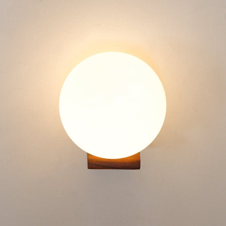 The sphere lit bright, warm light spilling onto the wall around it