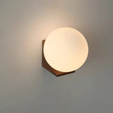 The walnut bracket and sphere lit warm against a plain pale wall