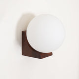 The walnut bracket lit warm with the sphere glowing above it