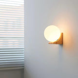 Sconce lit in a corner beside a window, the blind slats catching light