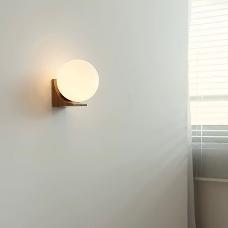 Sconce unlit on a pale wall beside a window with a white blind