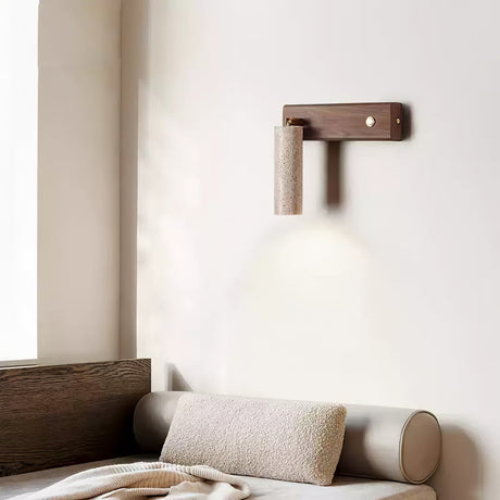 Sconce lit above a bed with a bolster, the beam washing the wall above