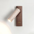 Travertine tube lit on a walnut plate, the beam washing up the wall