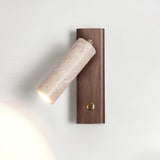 Travertine tube lit on a walnut plate, the beam washing up the wall