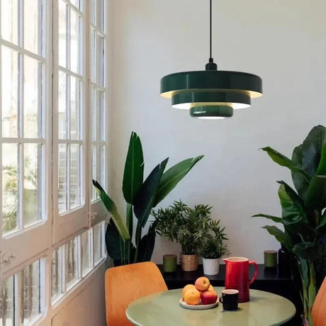 Minimalist ceiling light with a layered metal shade in green above a table