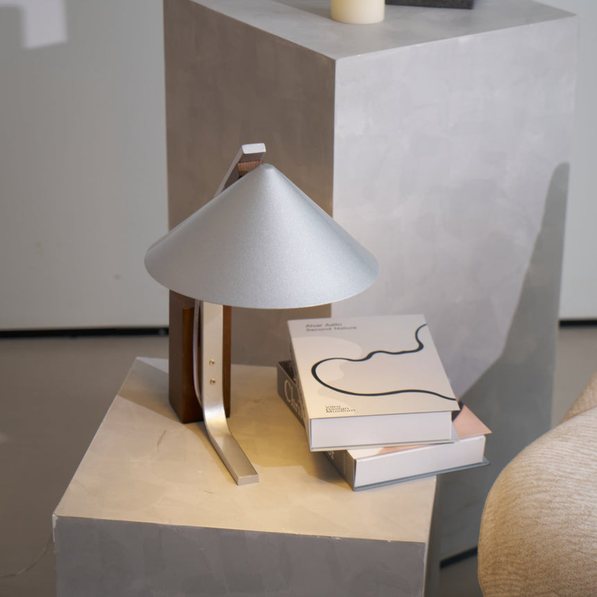 Minimalist desk lamp seen from above beside two books on a plinth