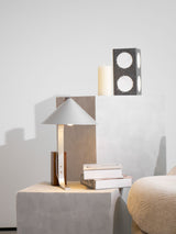Minimalist desk lamp on a plinth beside a candle and framed art