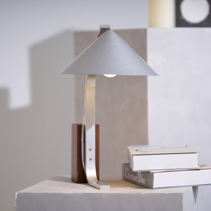 Minimalist desk lamp lit on a plinth in a pale living room