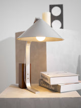 Minimalist desk lamp lit in front of a framed print on a wall
