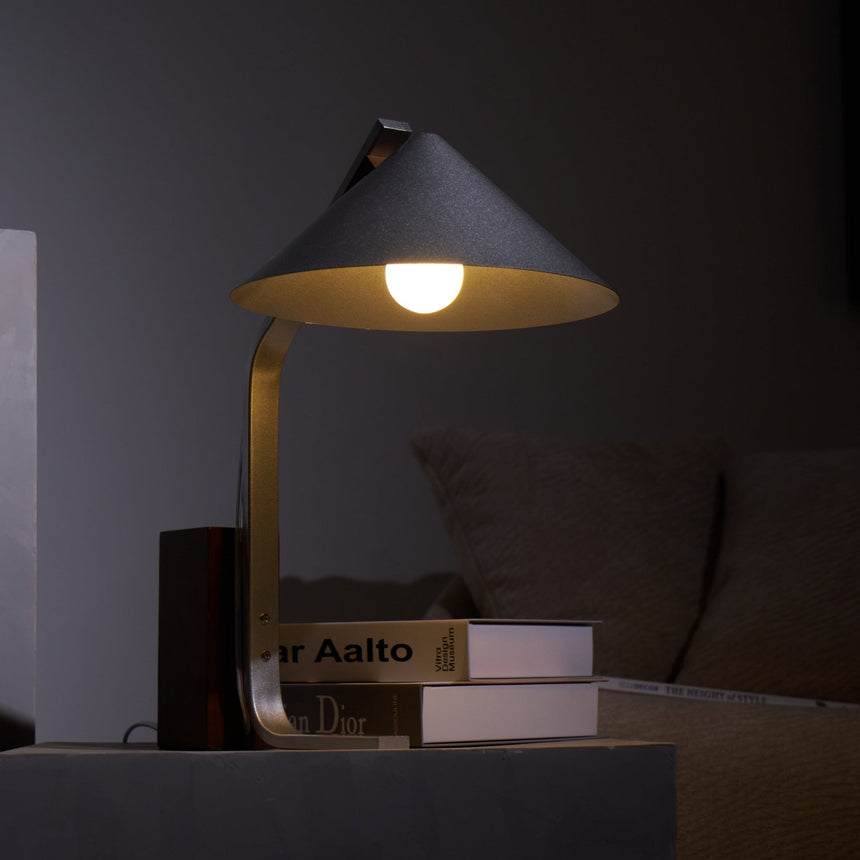 Minimalist desk lamp lit close in the dark, the bulb visible below