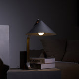 Minimalist desk lamp lit in a dark interior beside books