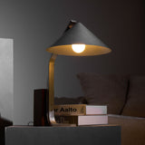 Minimalist desk lamp lit in a dark room over a stack of books