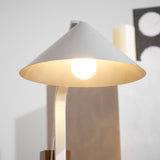 The cone shade of the desk lamp lit and seen close from below