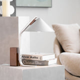 Minimalist desk lamp unlit on a pale plinth beside books
