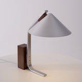 Minimalist desk lamp on a plain ground with the walnut block at left