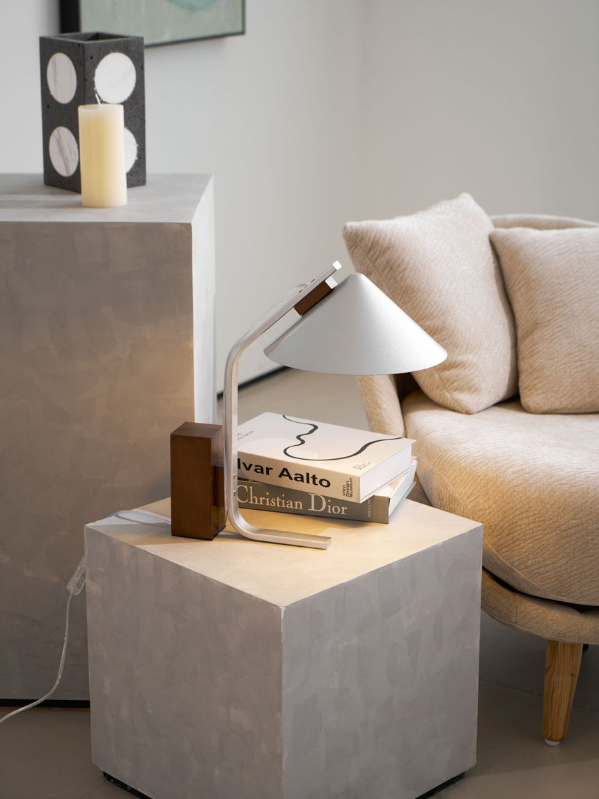 Minimalist desk lamp seen from above on a pale concrete cube