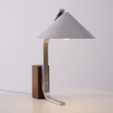 Minimalist desk lamp on a plain ground with the switch in view