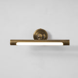 The bronze bar lit along its length, the diffuser bright below the round plate