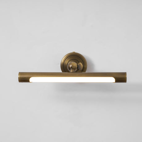 The bronze bar lit along its length, the diffuser bright below the round plate