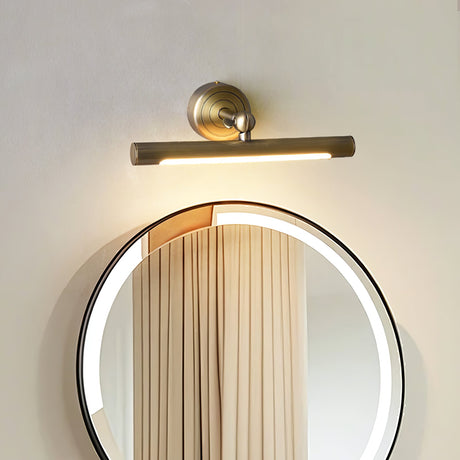 Bronze bar lit over a round mirror reflecting a curtain, the glow filling the glass