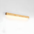 Light pine picture light bar lit against a plain pale wall