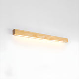 Light pine picture light bar lit against a plain pale wall