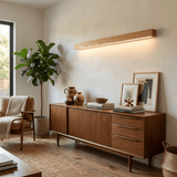 Walnut bar lit on the wall above a sideboard and framed artwork