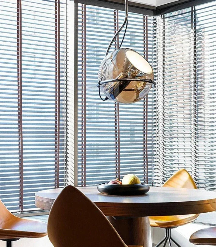 The globe hung above a dining table with tan chairs and a fruit bowl