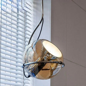 The mirrored globe tilted in its ring in front of a white window blind