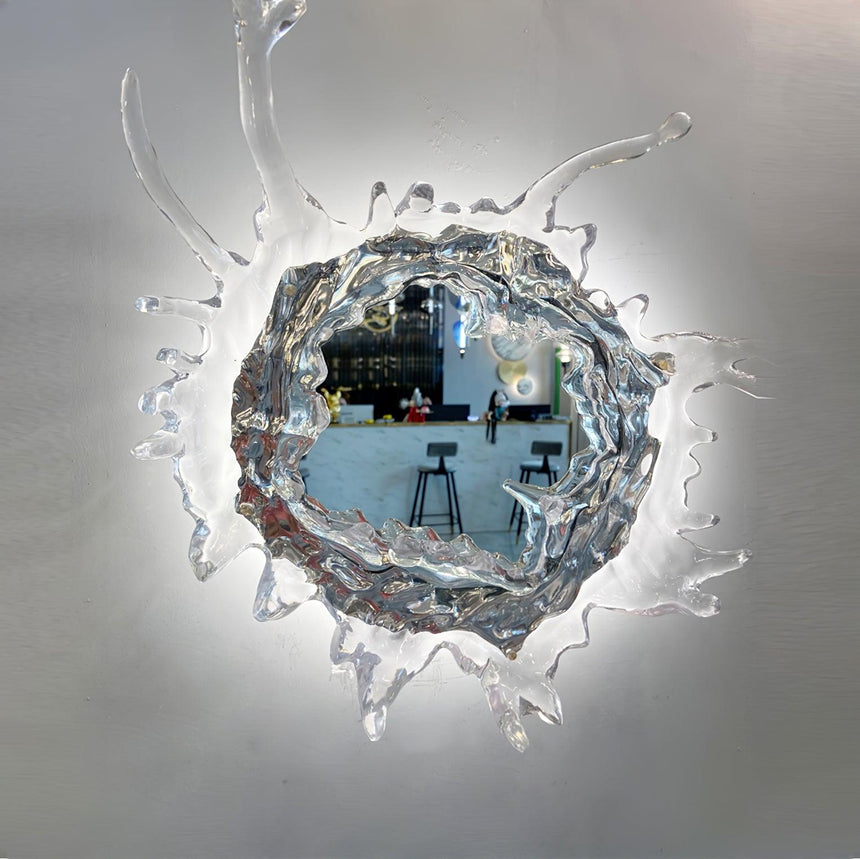 The mirror reflecting a room, framed by clear sculpted drops