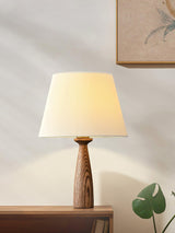 Ribbed shade lamp on a shelf in sunlight beside a small green plant