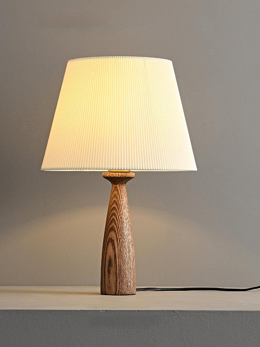 Ribbed shade lamp lit and seen from a slight angle on a gray surface