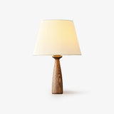 Table lamp with a ribbed white shade on a tapered open grain wood base