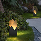 One lit on gravel beside a clipped shrub and a pale paved walk