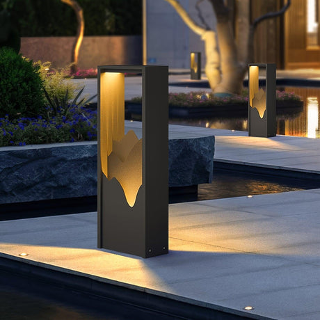 Two lit on paving beside a water feature with planting behind them