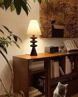 Rippled base lamp lit on a bookcase beside a framed print